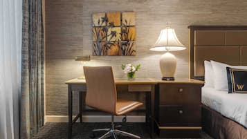 Une chambre d’hôtel équipée d’un lit, d’un bureau, d’une chaise, d’une lampe et d’une œuvre d’art murale.