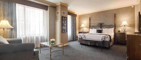 Una habitación de hotel con una cama, un sofá, una mesita y una lámpara.