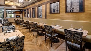 Un restaurant doté d’un plancher en bois, de longues tables et de chaises aux revêtements à motifs.