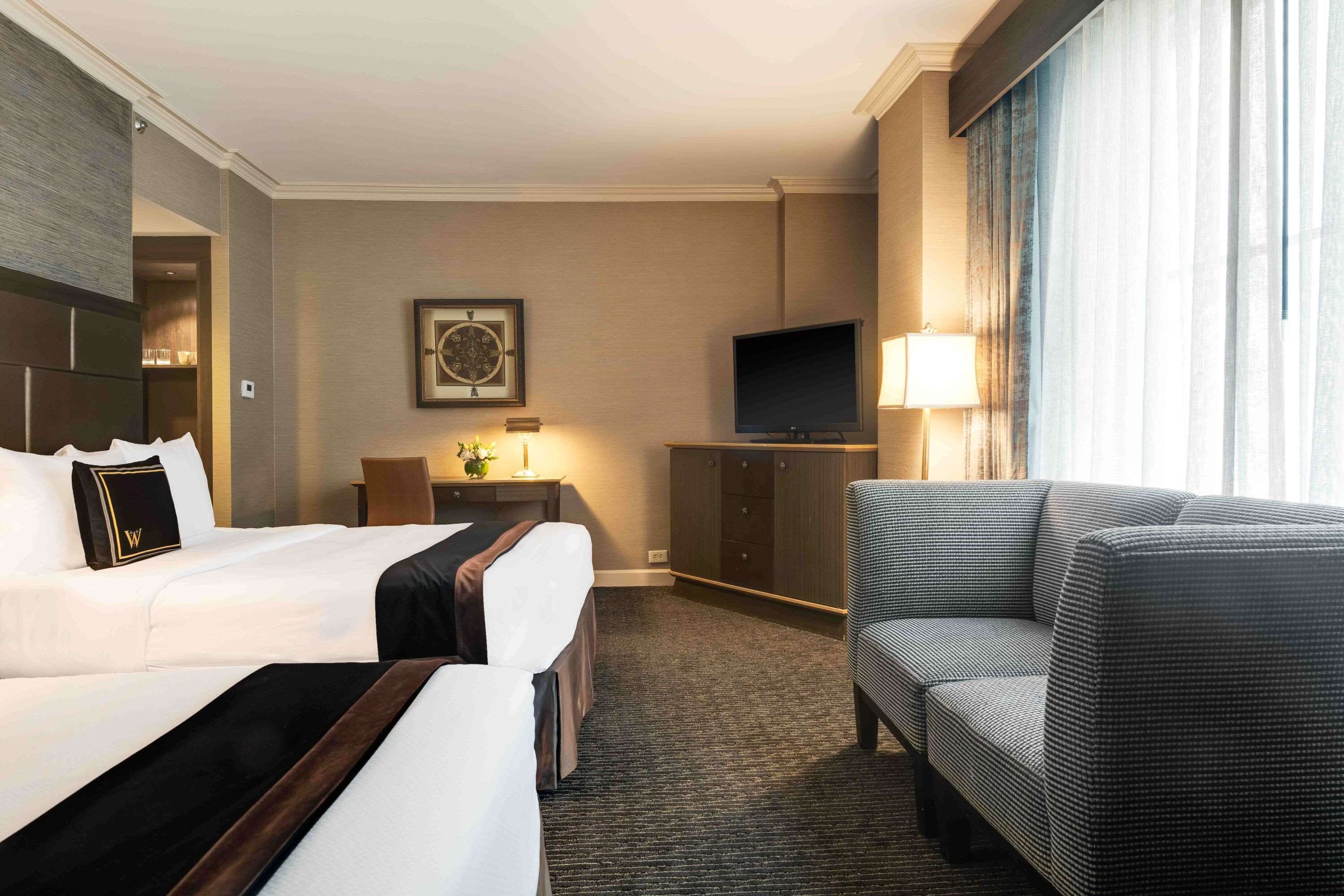 Een hotelkamer met een groot bed, een bank, een televisie en een bureau met een lamp.