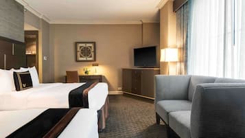 Een hotelkamer met een groot bed, een bank, een televisie en een bureau met een lamp.