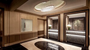 Une salle de bain luxueuse avec une grande baignoire ovale, un lustre et deux grands miroirs ornés de compositions florales.
