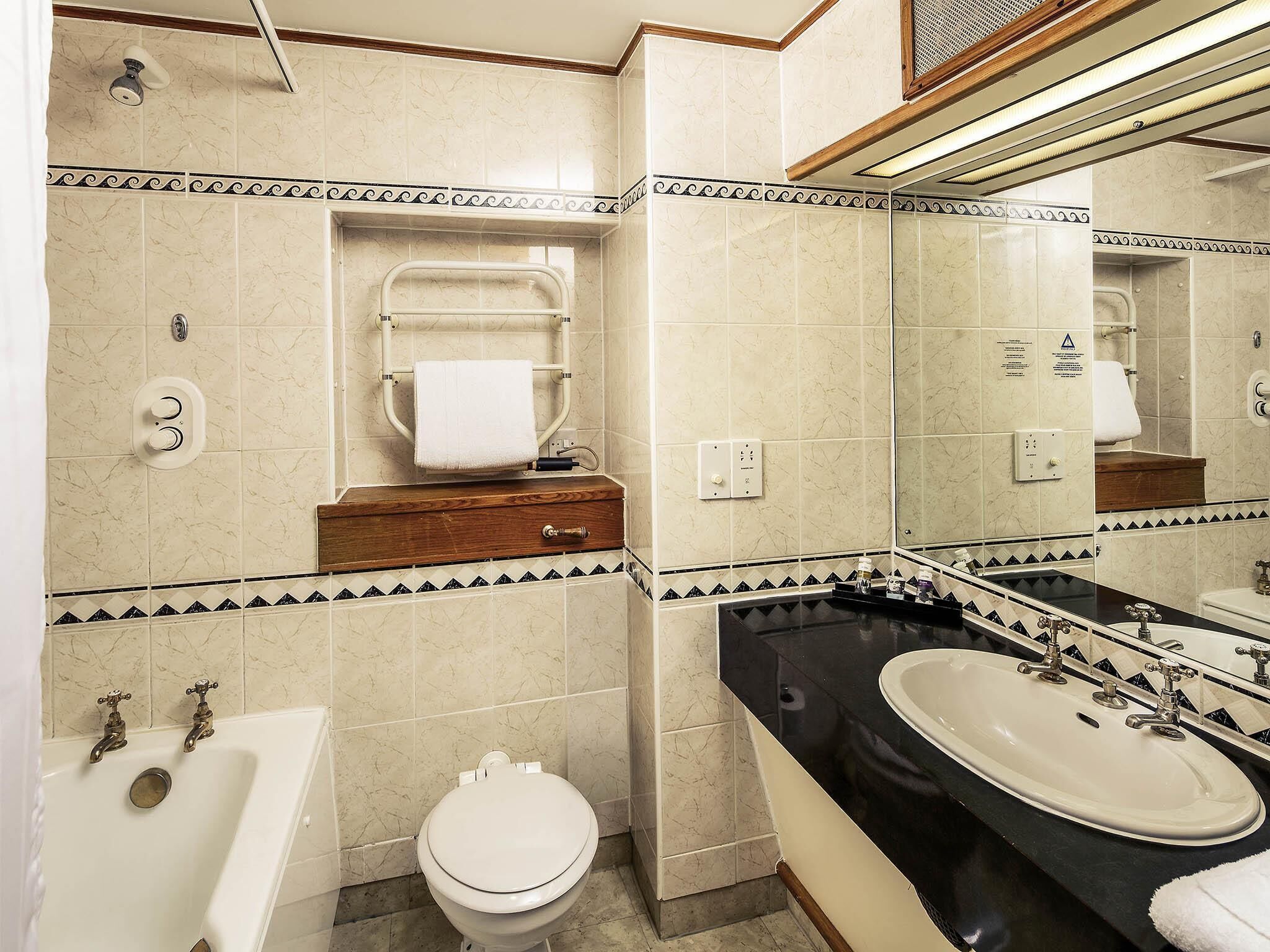 Un baño con bañera, inodoro, tocador y espejo.