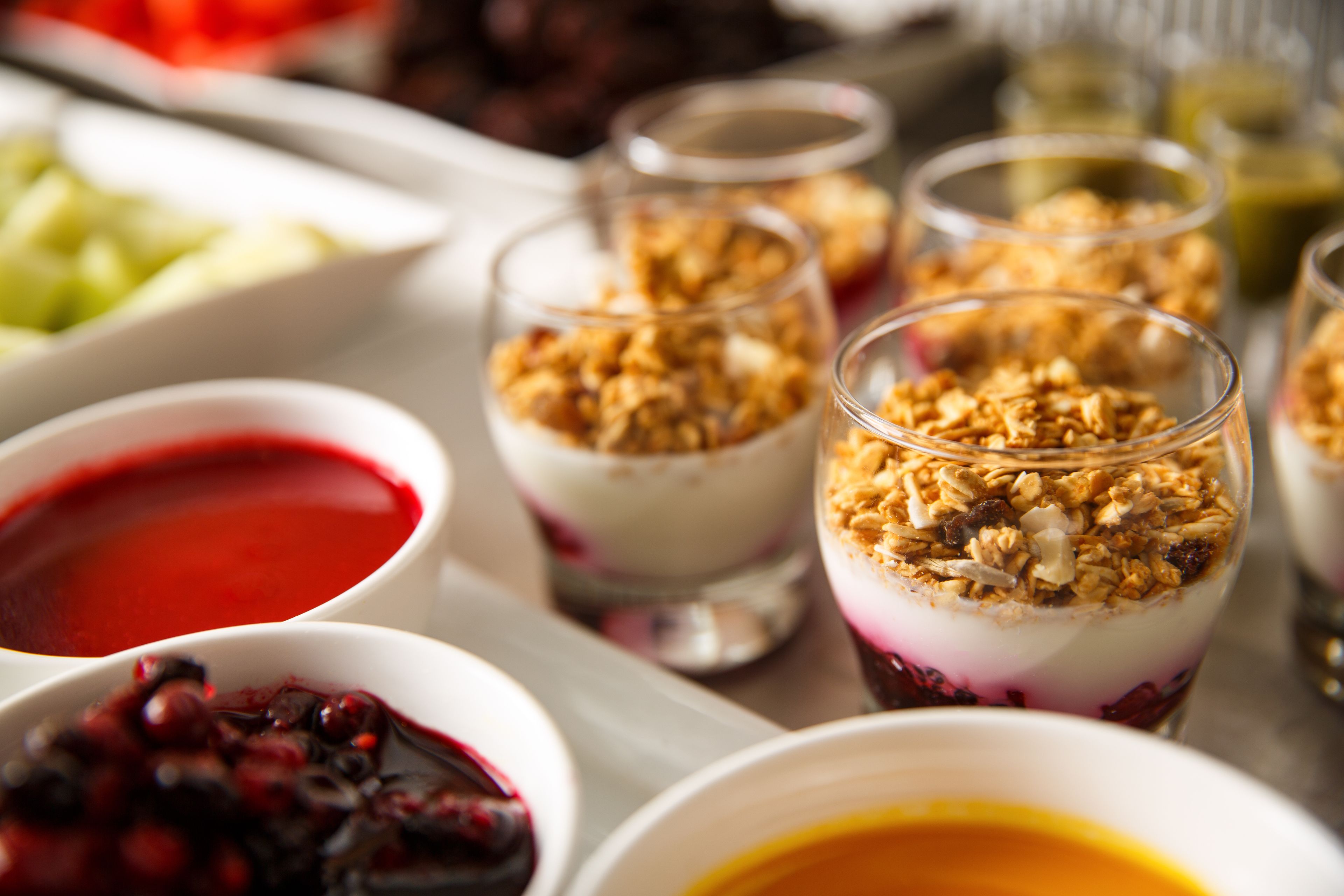A tray of desserts including parfaits and fruit compotes.