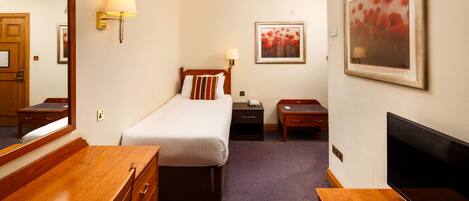 A hotel room with a bed, bedside tables, a dresser, a TV, and a painting on the wall.