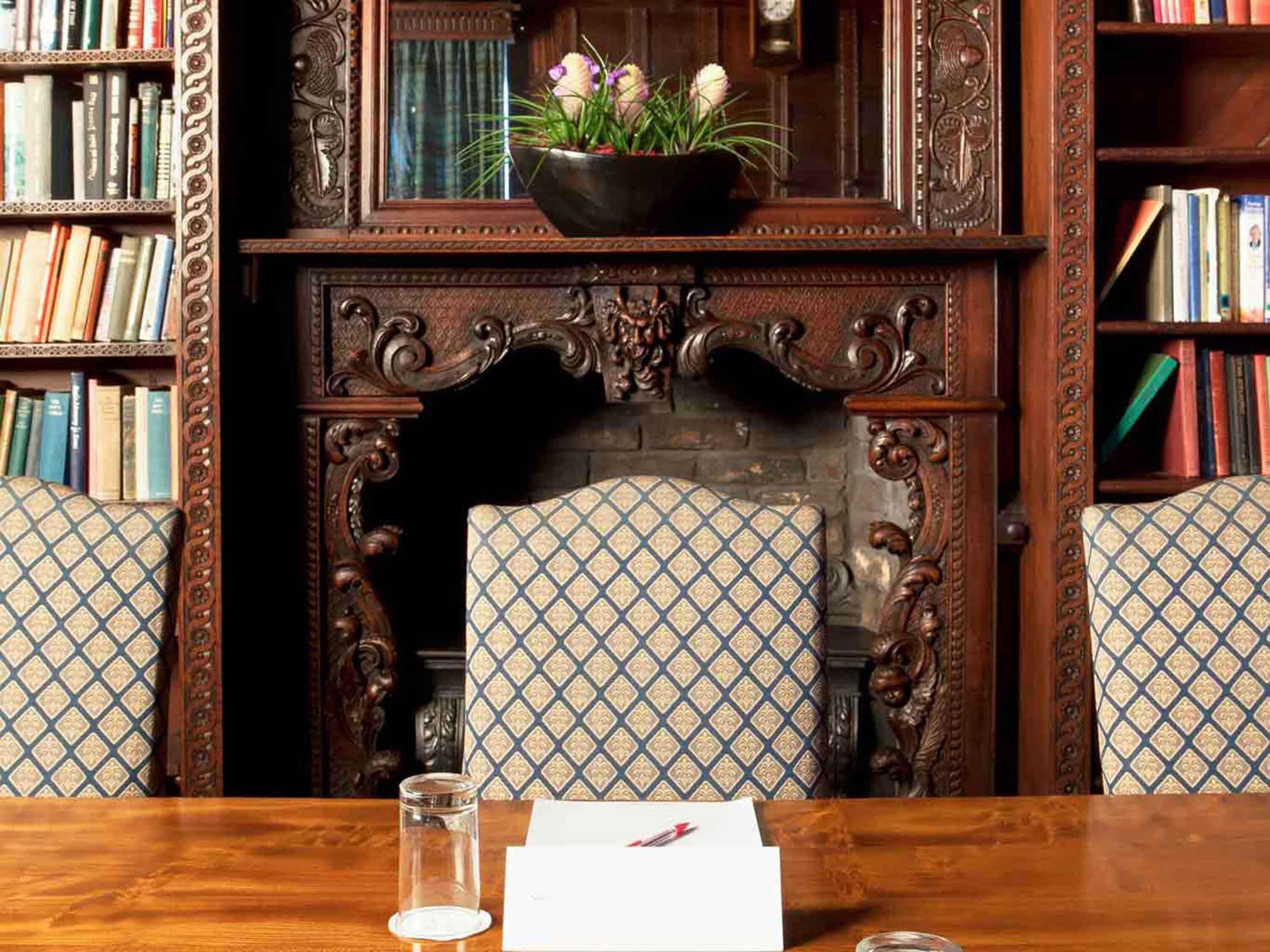 Una habitación con chimenea, estanterías y sillones con estampado.