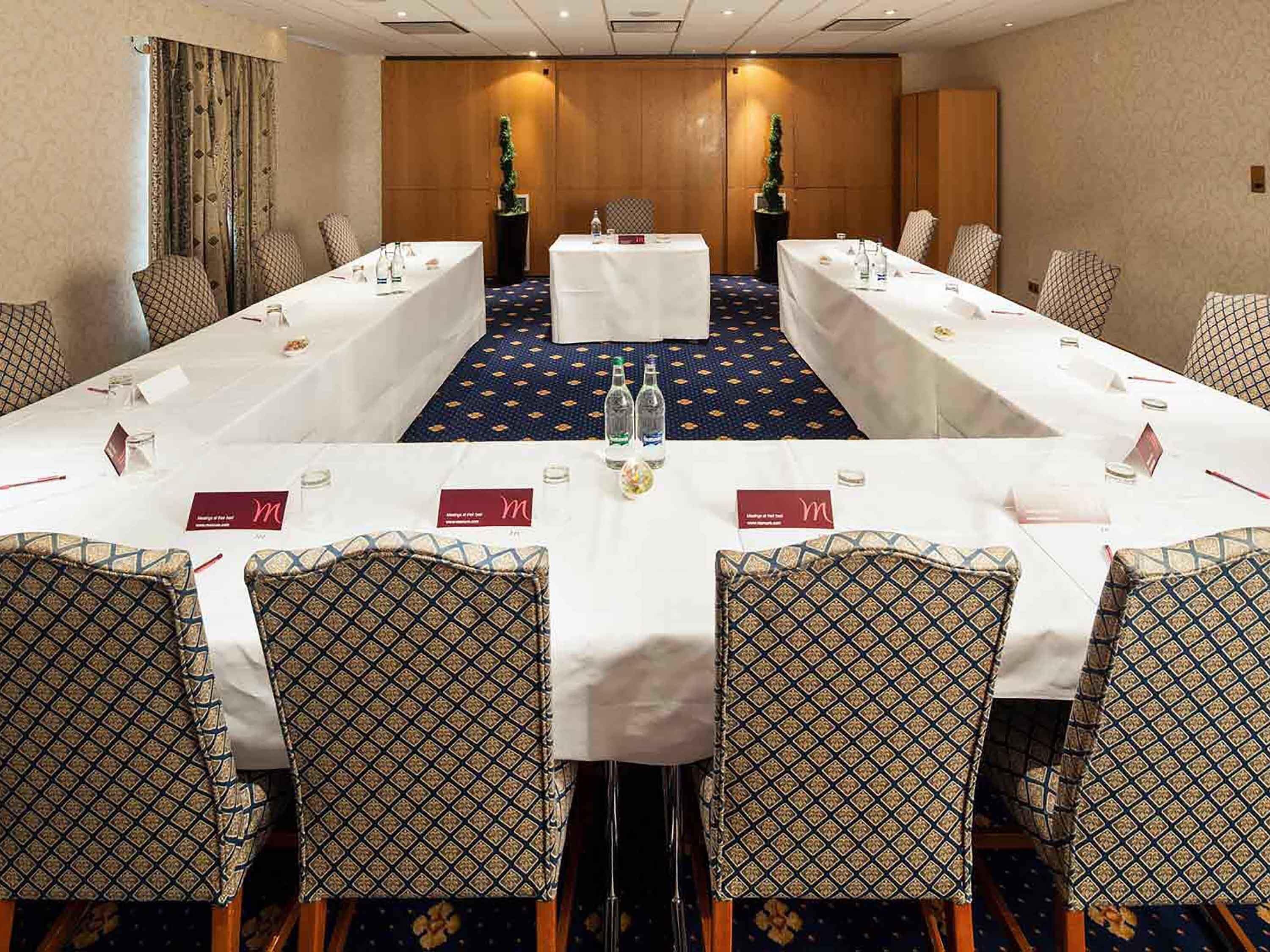 A conference room with a long table, chairs, name cards, and water bottles.