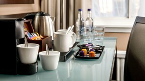 Habitación de hotel con kitchenette, que incluye cafetera, tazas, bandeja con condimentos y una lámpara.