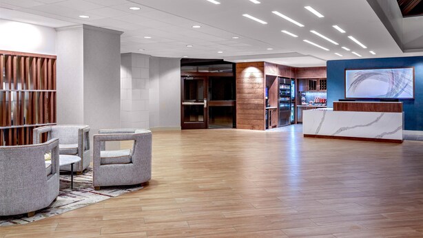 A spacious lobby with a reception desk, seating area, and a wooden floor. - DoubleTree by Hilton Hotel Boston - Westborough (Westborough)