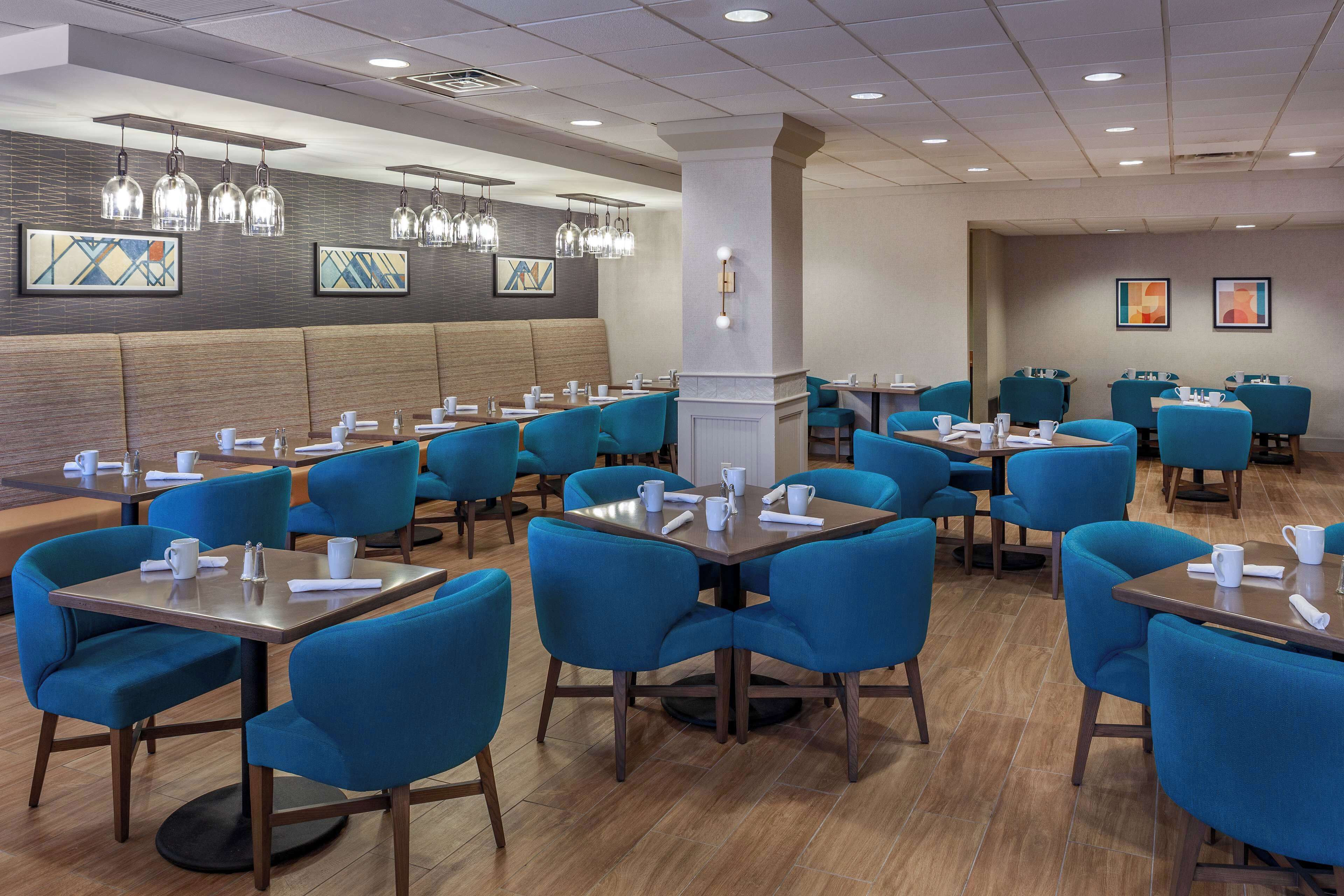 Un restaurant moderne avec des chaises et des tables bleues, un plancher en bois et des luminaires suspendus.
