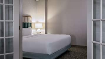 Una habitación de hotel con una cama, una mesita de noche, una lámpara y una ventana.