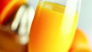 A glass of orange juice with a blurred background of oranges.