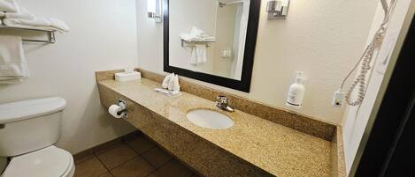 A bathroom with a toilet, sink, and mirror.