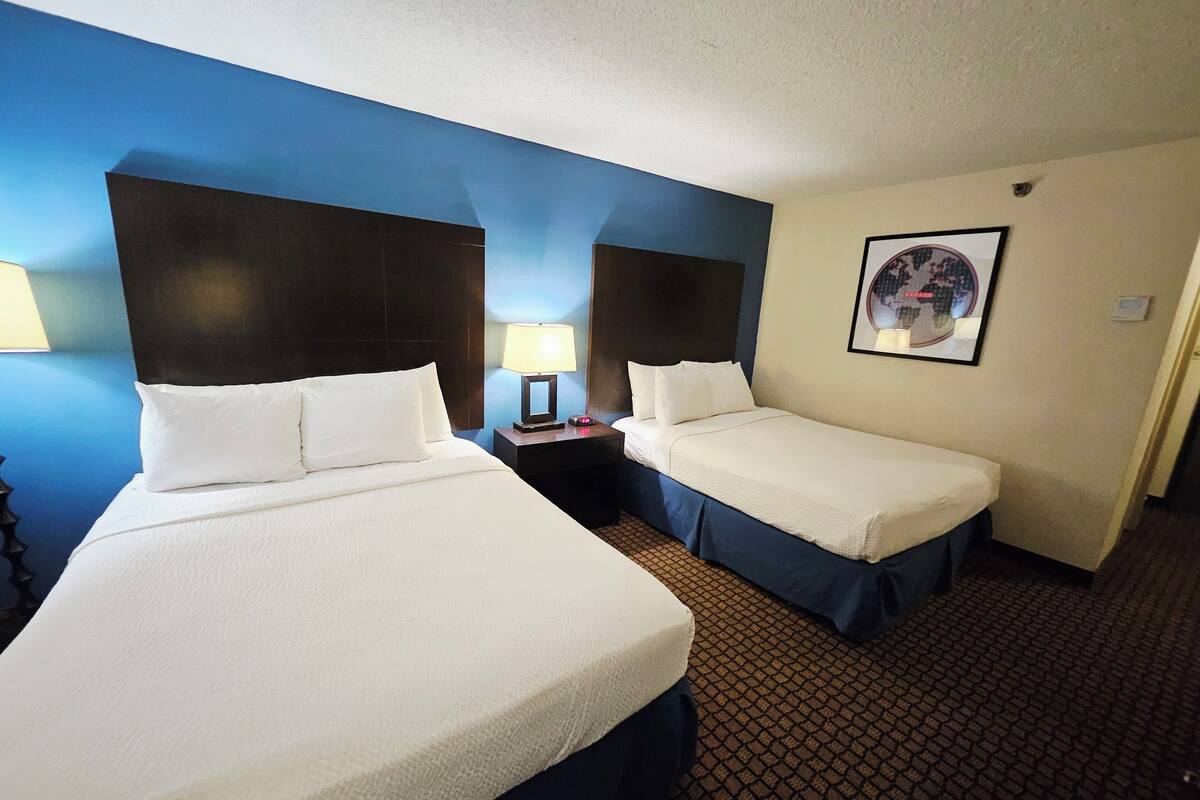 Two single beds with headboards, a nightstand with a lamp, and a framed picture on the wall.