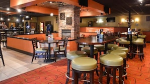 A restaurant with a central bar area, multiple seating tables, and high stools. - Ramada Plaza by Wyndham Sheridan Hotel & Convention Center (Sheridan)