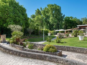 Un jardin aménagé avec un sentier en pierre, des espaces de détente en plein air et un bâtiment au design moderne.