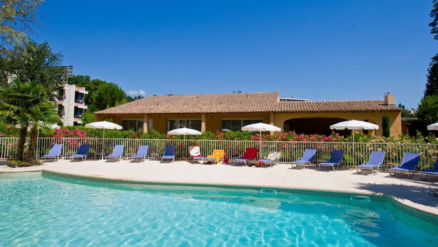 A swimming pool with lounge chairs and umbrellas, surrounded by a fence and greenery. - Hotel Novotel Aix en Provence Pont de l'Arc Fenouillères (Aix-en-Provence)