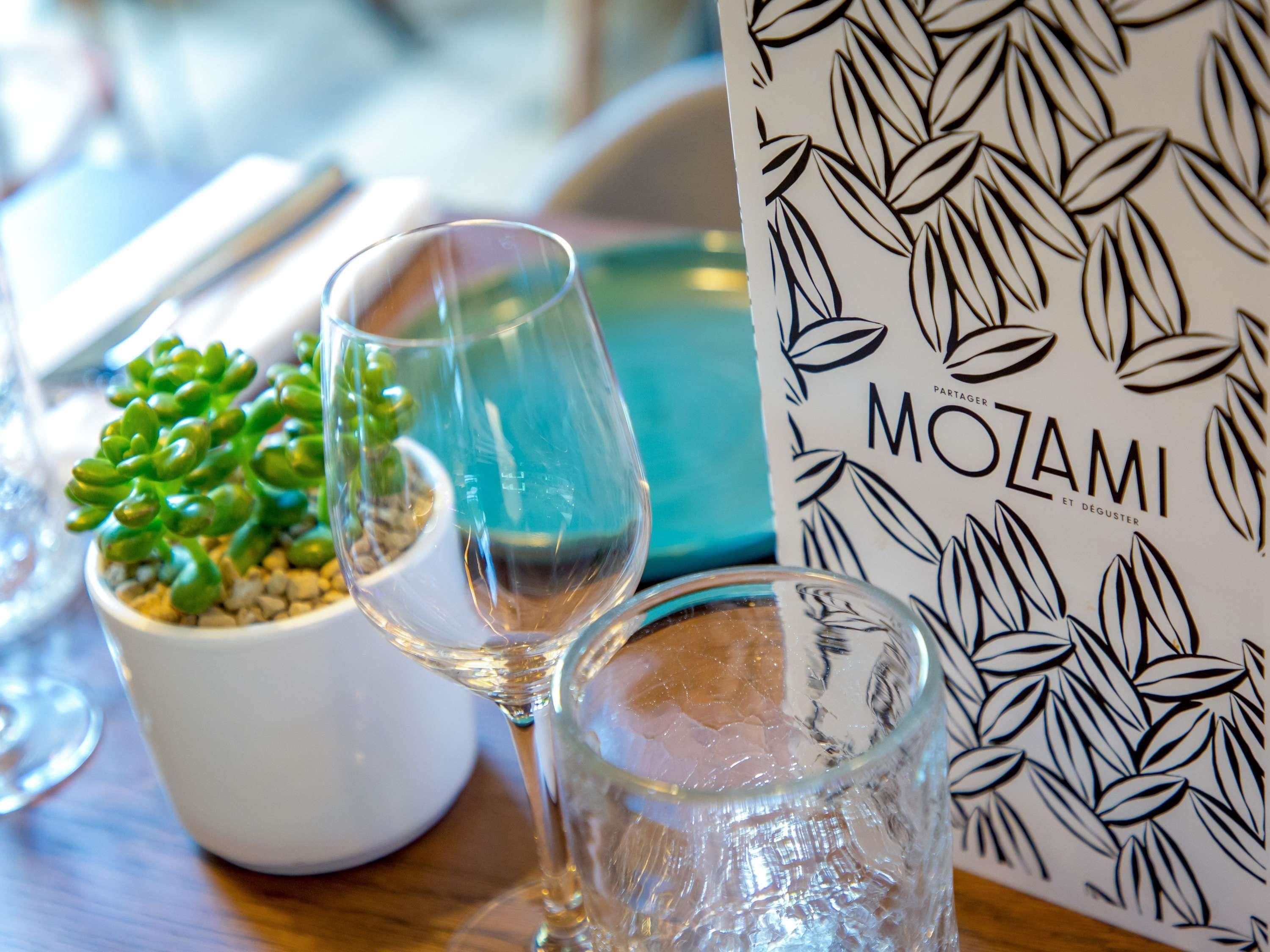Uma mesa com uma suculenta em vaso, dois copos de vinho e um menu com padrão de folha.