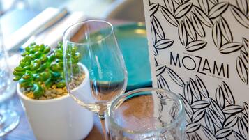Uma mesa com uma suculenta em vaso, dois copos de vinho e um menu com padrão de folha.
