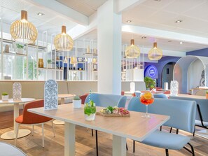 A modern restaurant interior with high ceilings, pendant lighting, and a seating area with tables and chairs. - Hotel Novotel Aix en Provence Pont de l'Arc Fenouillères (Aix-en-Provence)