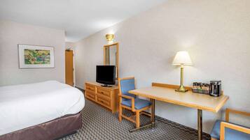 Une chambre d’hôtel équipée d’un lit, d’un bureau avec une lampe, d’une télévision et d’une machine à café.