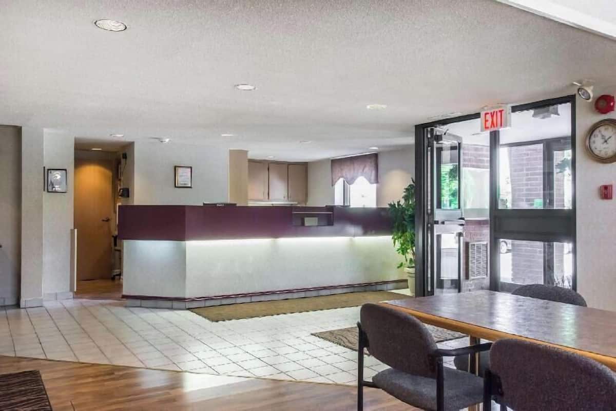 A reception area with a desk, chairs, a clock, and an exit sign.