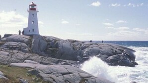 A lighthouse on a rocky outcrop with the ocean in the background.