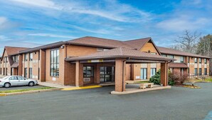 A multi-story hotel with a brick facade, large windows, and a covered entrance area.