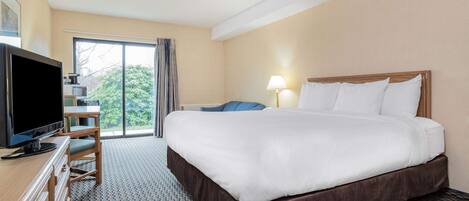 A hotel room with a large bed, a television, a desk, and a chair.