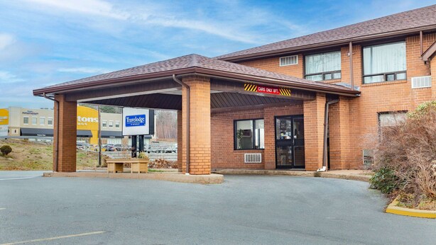 A brick building with a covered parking area and a sign indicating 'Cars Only 8ft.'