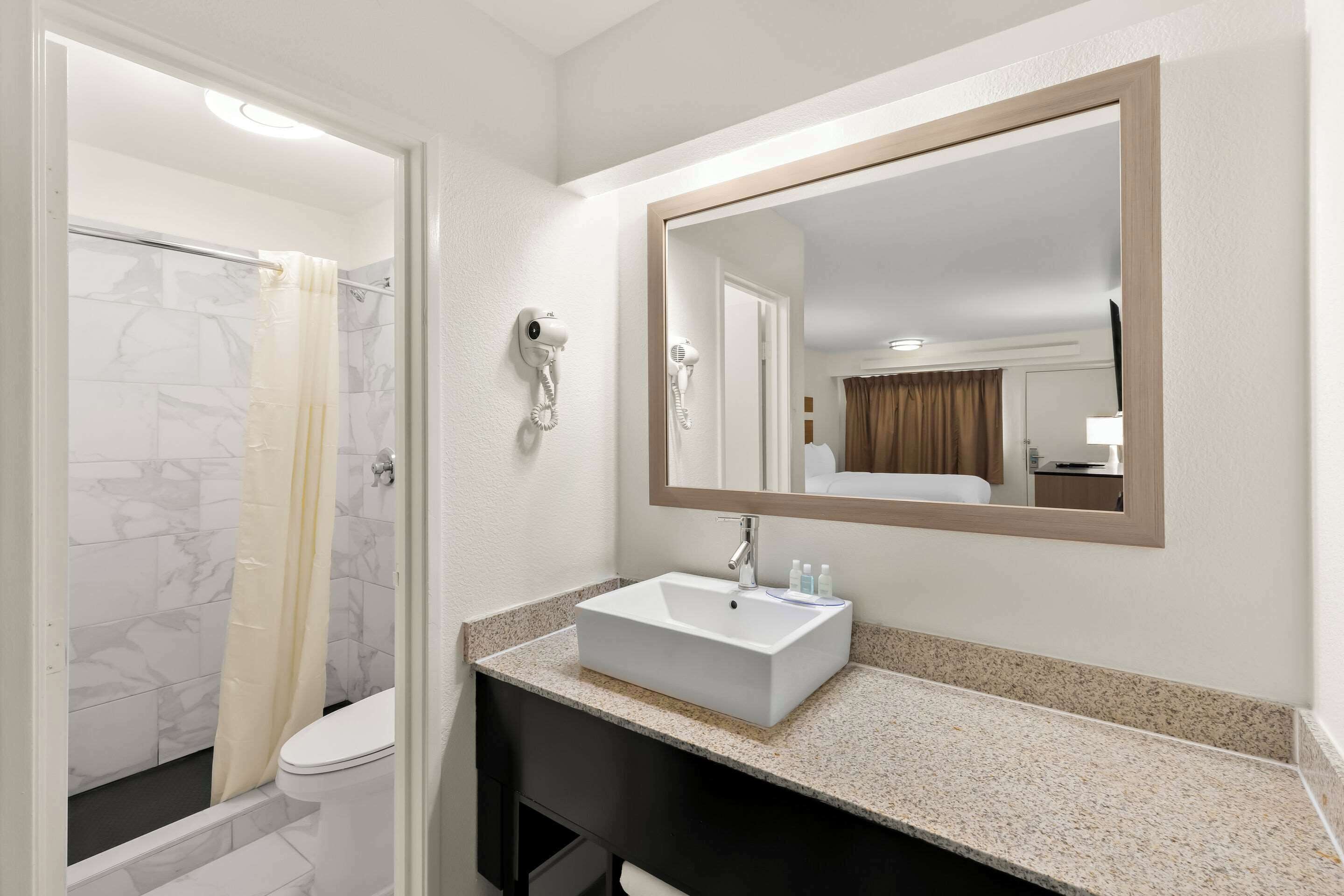 Une salle de bain avec un lavabo blanc, un miroir et un rideau de douche.