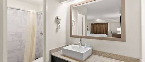 Une salle de bain avec un lavabo blanc, un miroir et un rideau de douche.