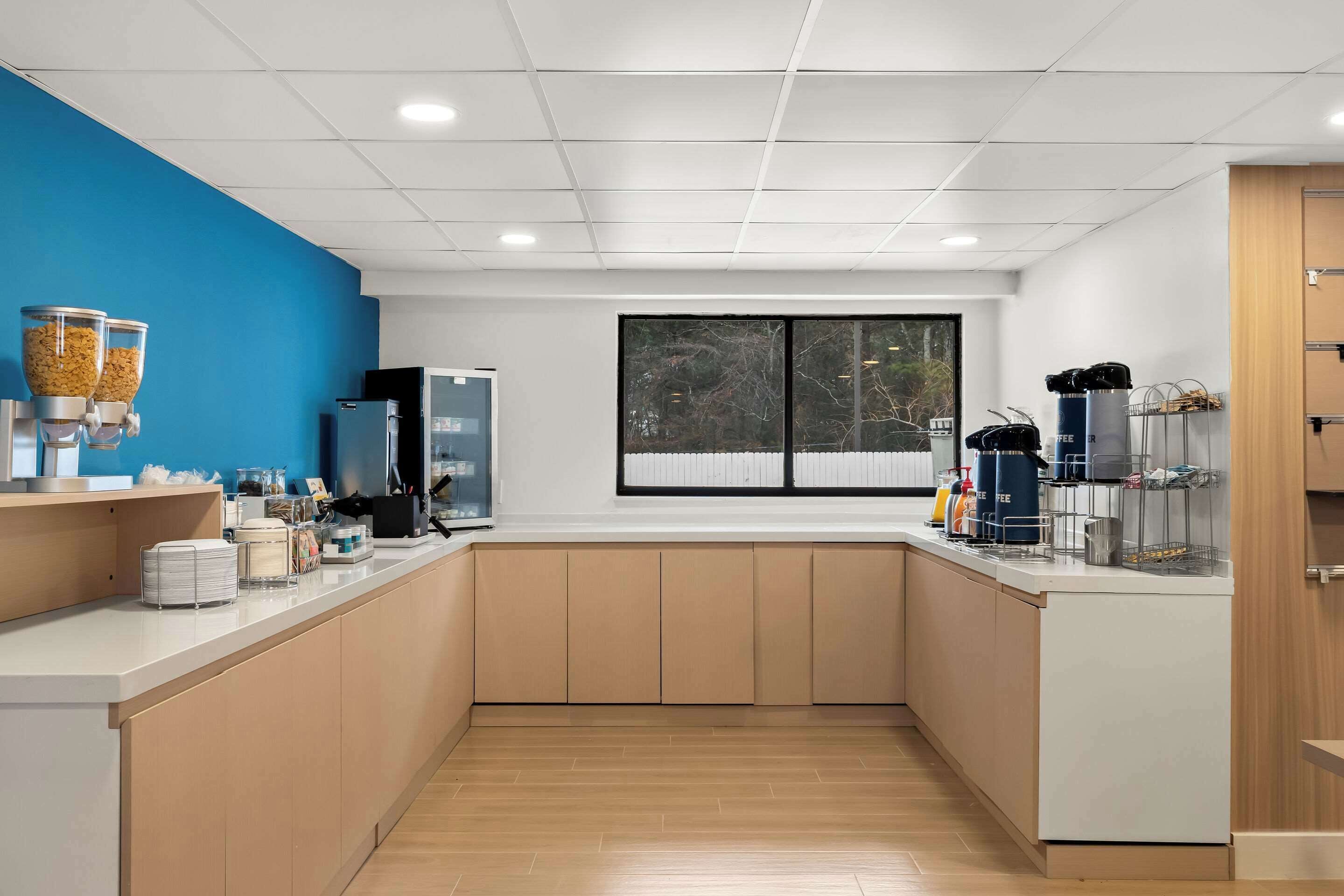 Una cocina moderna con una pared azul de acento, un ventanal grande y una estación de café.