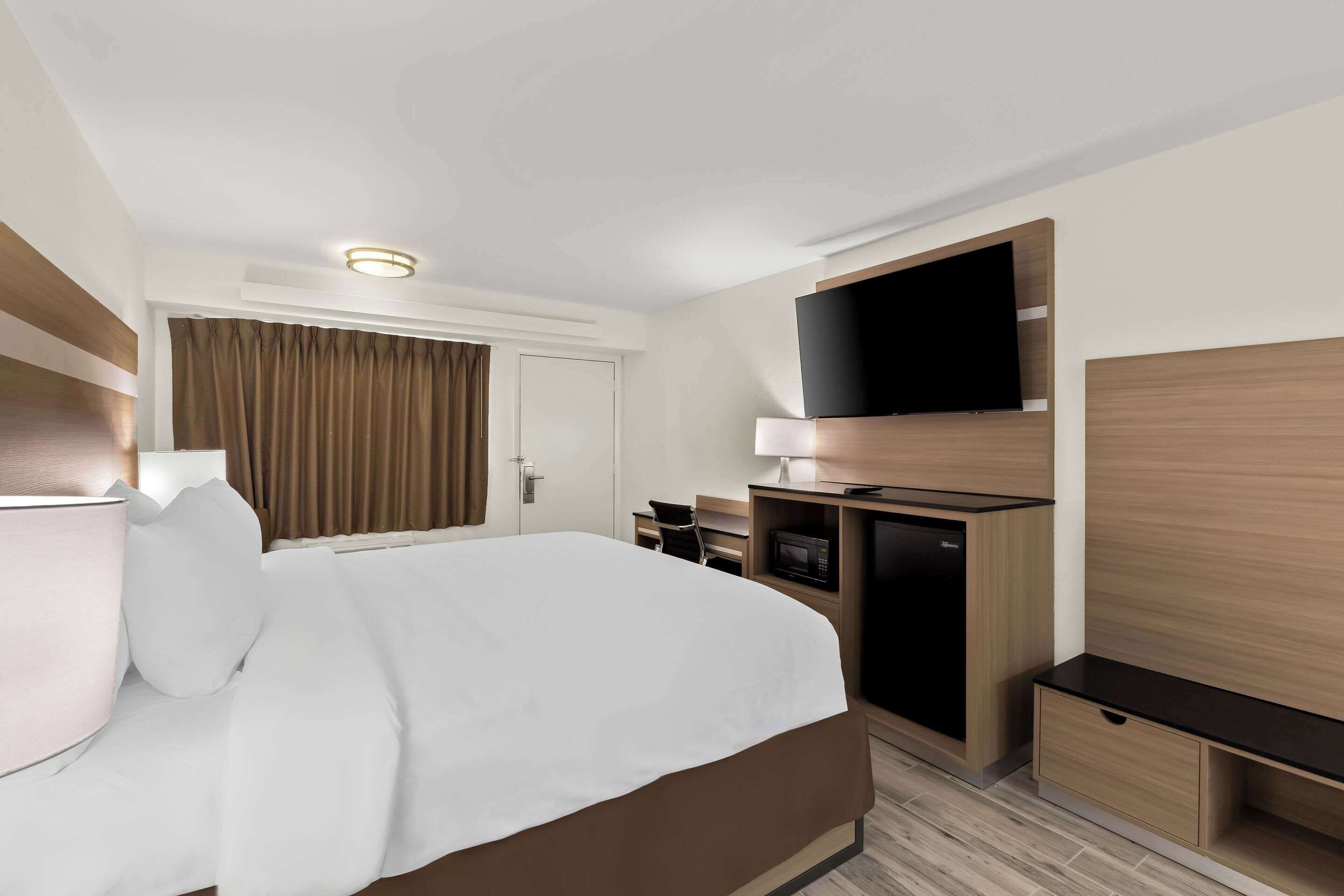 Een hotelkamer met een groot bed, een bureau met een computer, een flatscreen-tv en een magnetron.