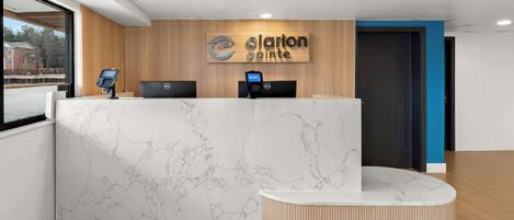 Un mostrador de recepción con diseño de mármol, un panel de pared de madera y un letrero que dice "Clarion Pointe".