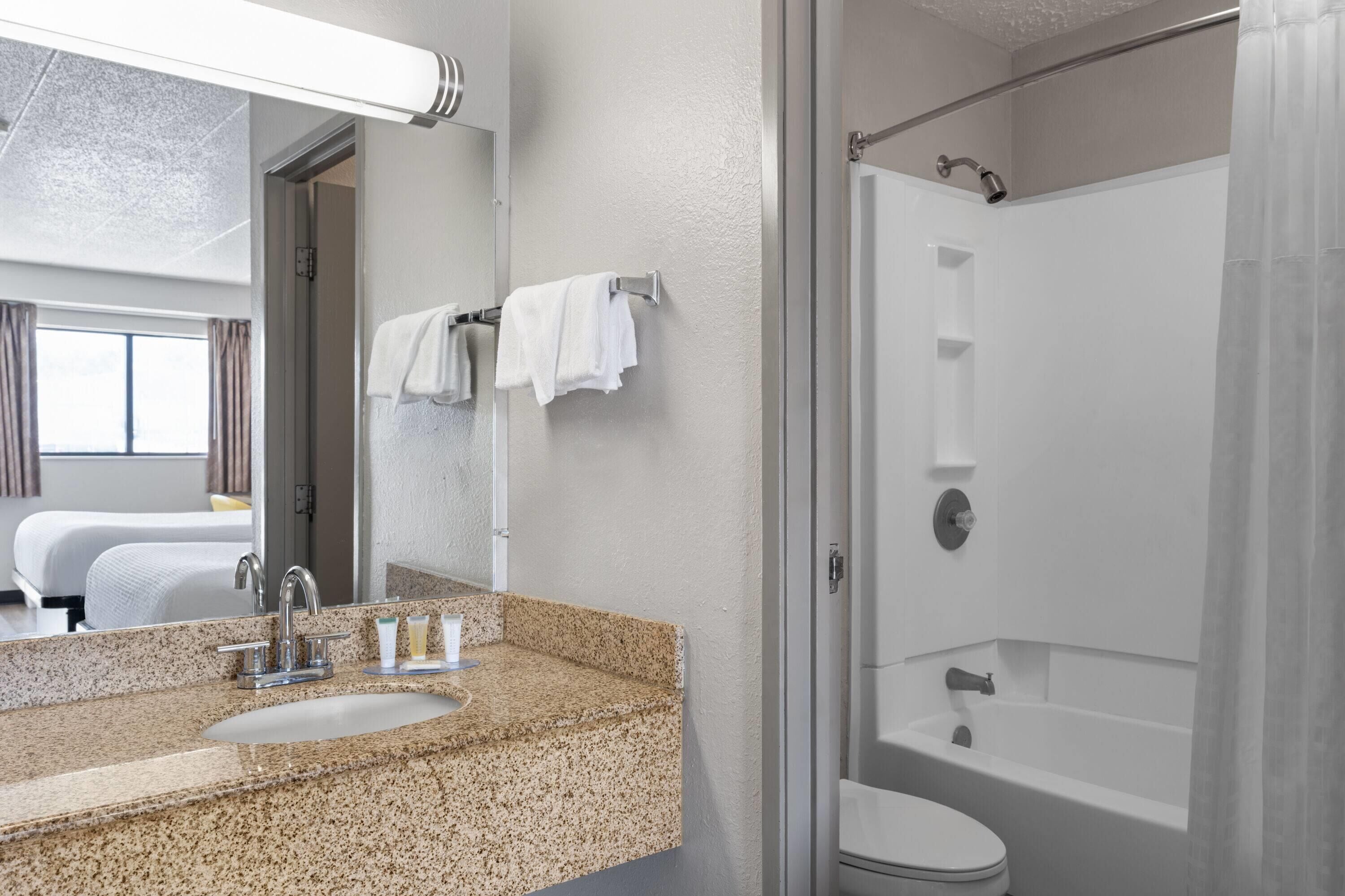 Une salle de bain moderne avec un lavabo en granit, un miroir, une douche et des toilettes.