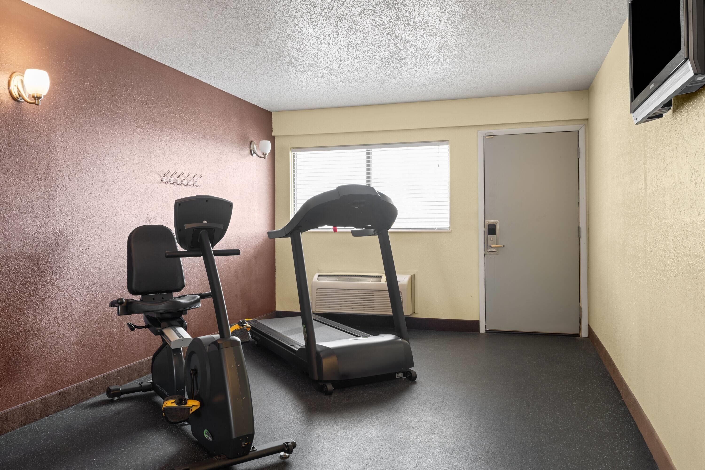 A small gym with a stationary bike, elliptical, and treadmill.