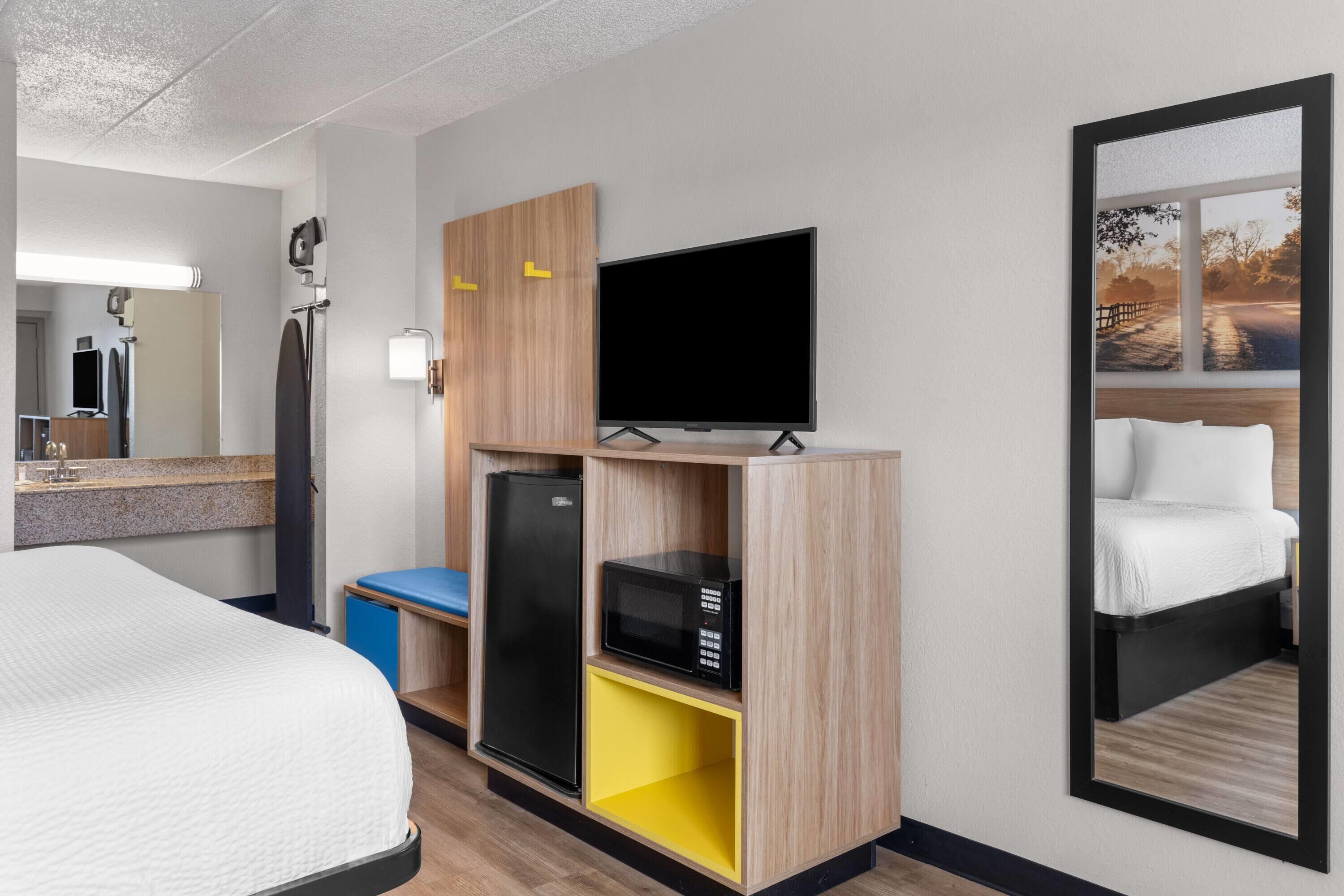 Habitació d'hotel amb un llit, televisió de pantalla plana, microones i nevera.