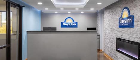 Un espace d’accueil avec une enseigne Days Inn, un comptoir de réception, un téléviseur à écran plat et un mur à l’aspect pierre.