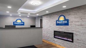 A reception area with a stone wall, a fireplace, and a reception desk. - Days Inn by Wyndham Cloverdale Greencastle (Cloverdale)