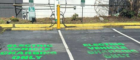 A parking area marked for electric vehicle charging, with a yellow bollard and charging station.