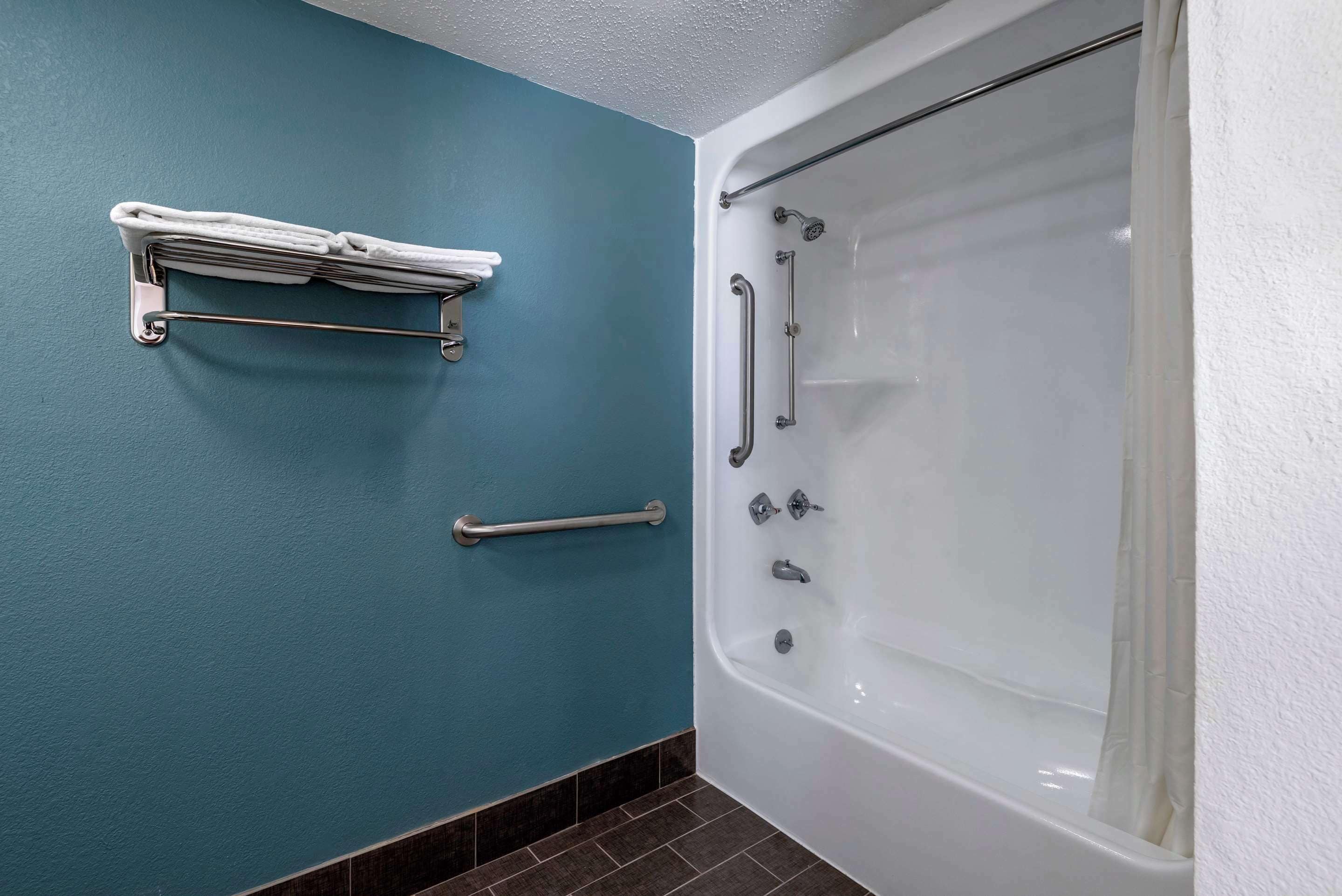 Un baño con bañera, toallero y baranda.