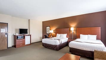 A hotel room with two beds, a desk, a television, and a minibar.