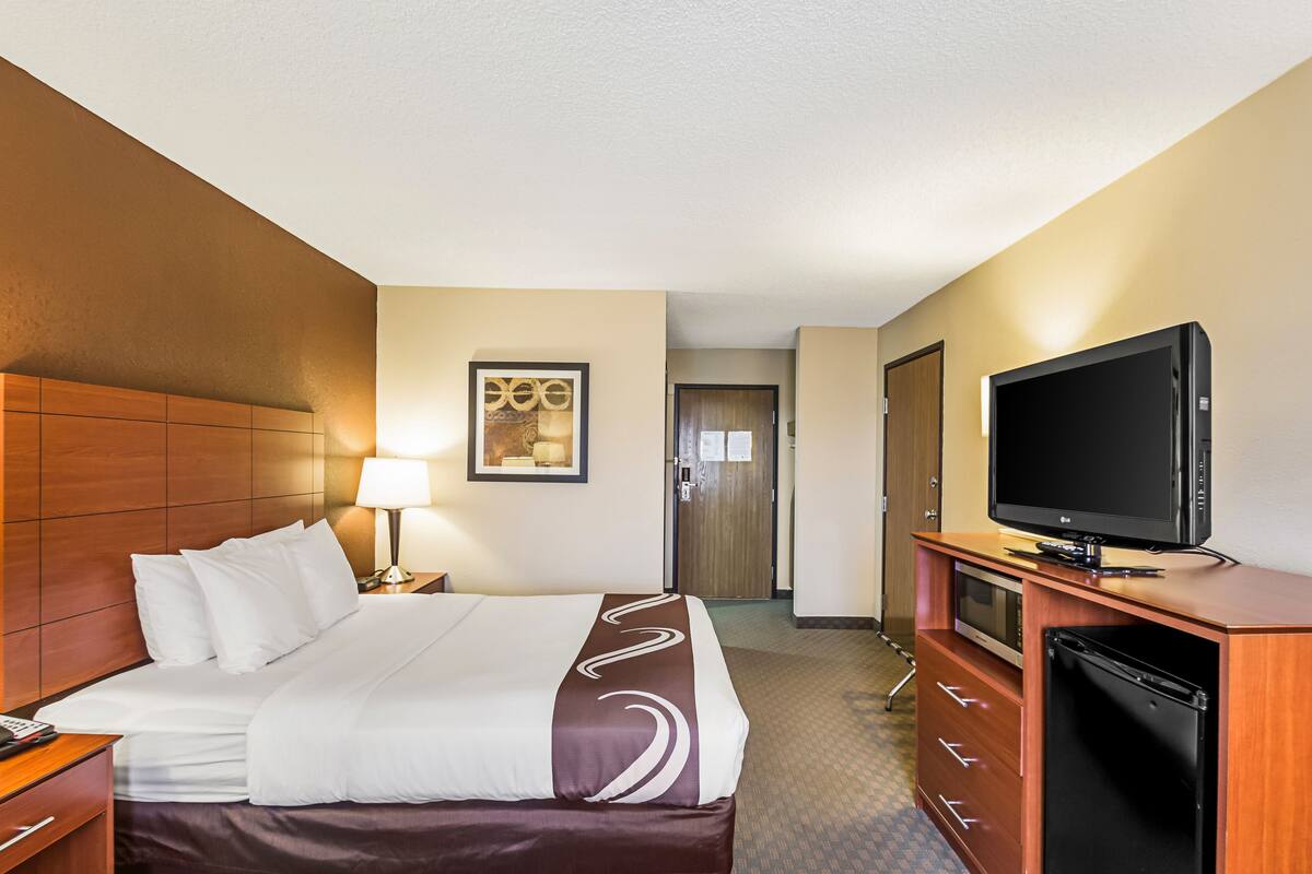Una habitación de hotel con cama, televisión, escritorio y armario.