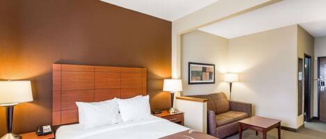 A hotel room with a large bed, two bedside tables, a chair, and a small table.