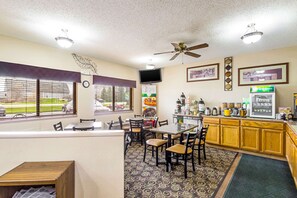 A restaurant with a counter, dining area, and kitchen.