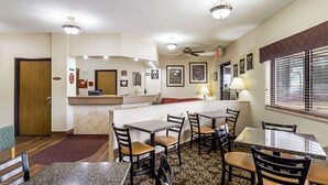 A hotel dining area with tables, chairs, a reception desk, and a ceiling fan. - Quality Inn Sheboygan North I-43 (Sheboygan)