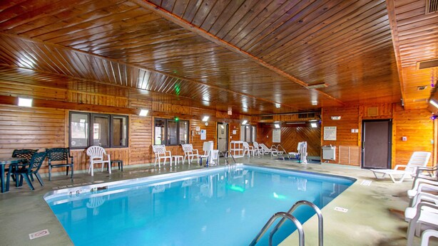 An indoor swimming pool with wooden walls and ceiling, surrounded by white lounge chairs and tables. - Quality Inn Sheboygan North I-43 (Sheboygan)