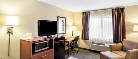 Ein Hotelzimmer mit Bett, Schreibtisch mit Computer, Fernseher, Mikrowelle und Minikühlschrank.