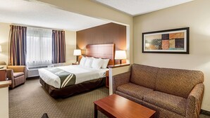 A hotel room with a bed, a sofa, a desk, and a painting on the wall. - Quality Inn Sheboygan North I-43 (Sheboygan)